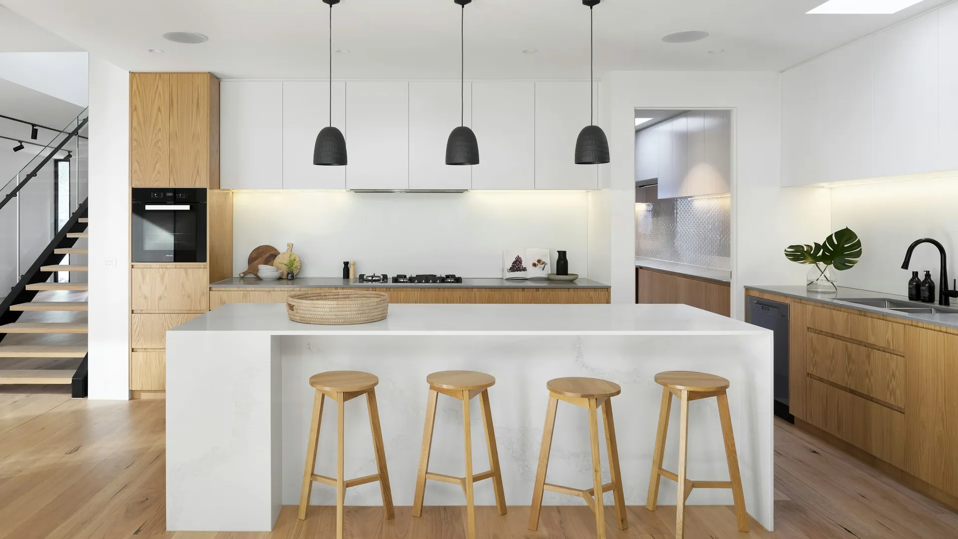 Cucina bianca con isola e sgabelli in legno